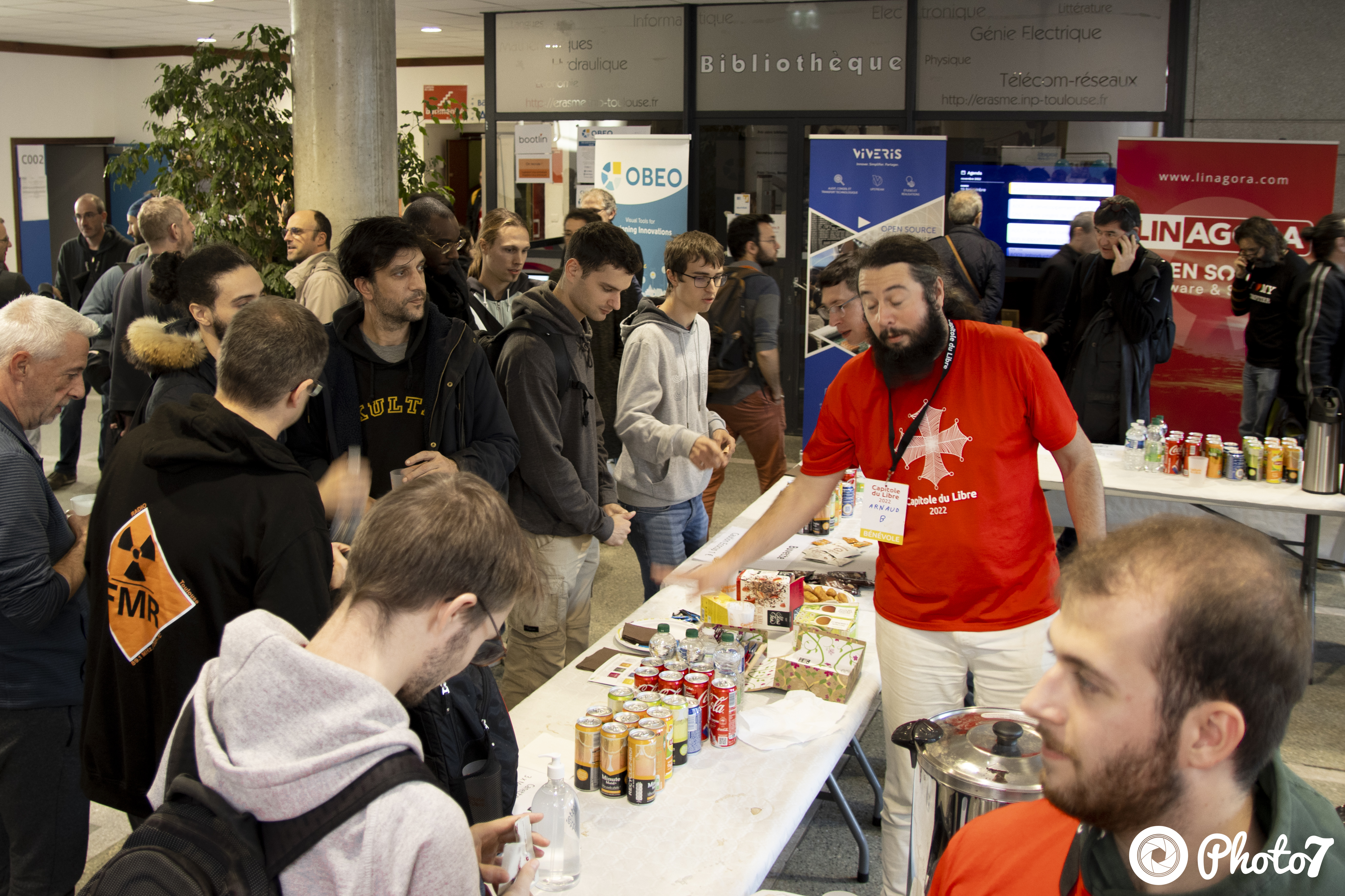 Bénévole servant des boissons au stand buvette avec banners de sponsors