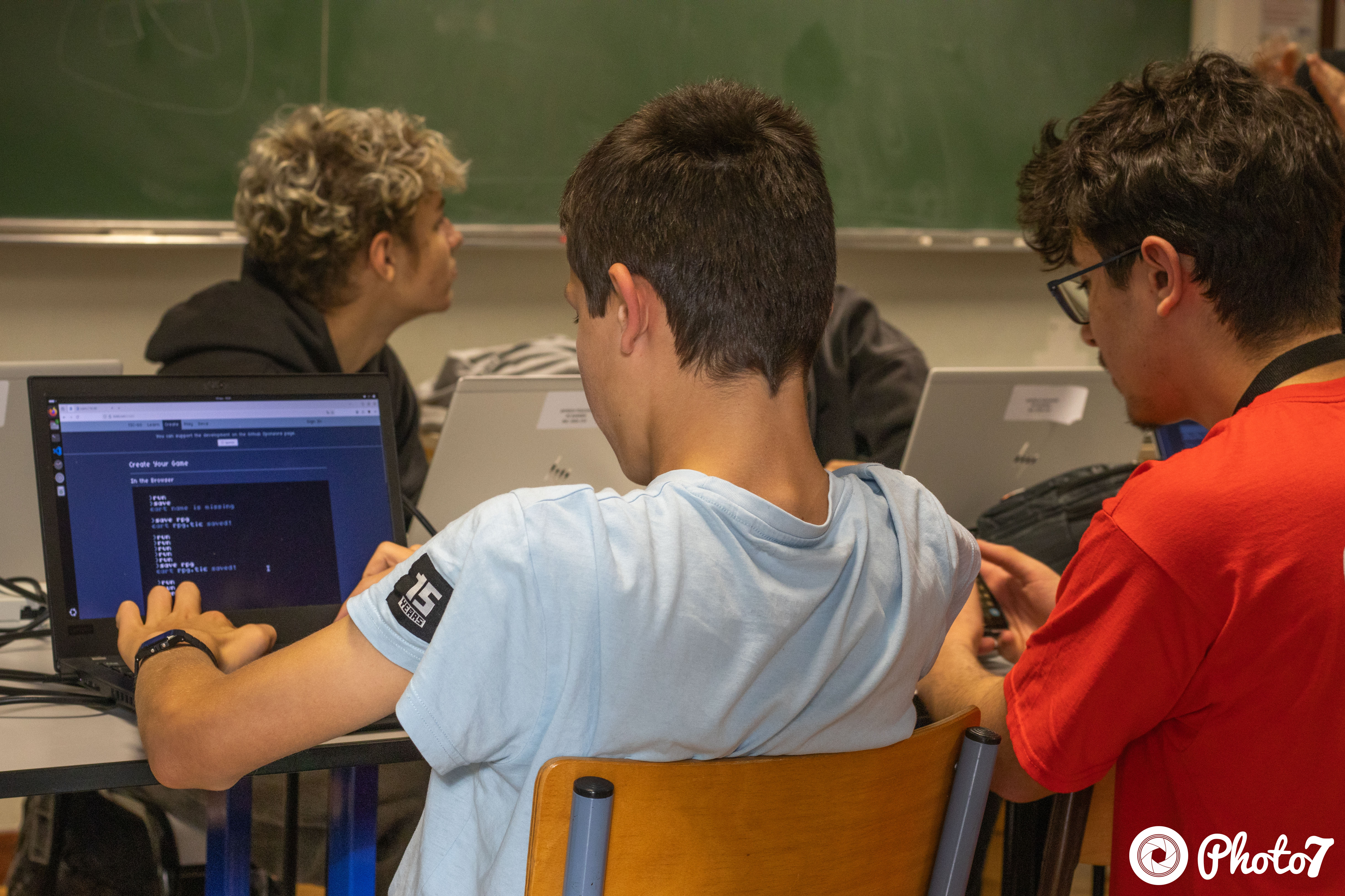 Trois adolescents collaborant sur du code dans un terminal pendant un atelier