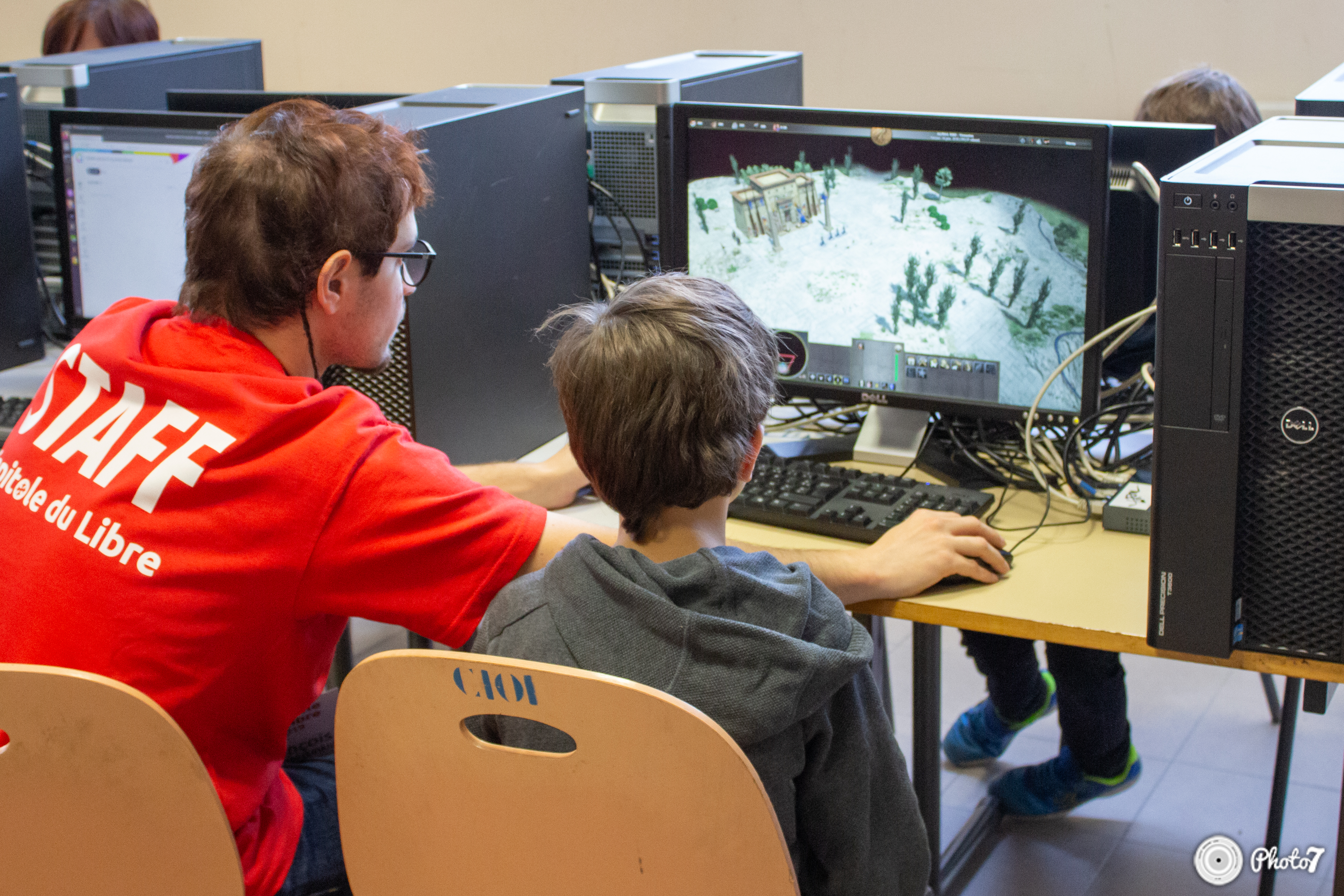 Bénévole staff aidant un enfant à jouer à 0 A.D. pendant la LAN party